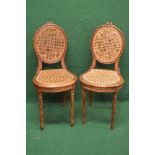 Pair of stained beech side chairs having oval caned backs with carved frames supported on swept