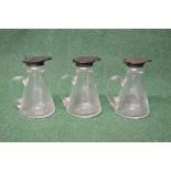Set of three silver topped glass whisky noggins having conical shaped bodies with star cut bases