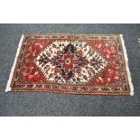 Red and cream ground rug having red, blue and black pattern with end tassels - 38.