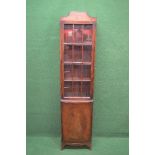 Narrow mahogany glazed bookcase having shaped pediment over glazed door opening to reveal three