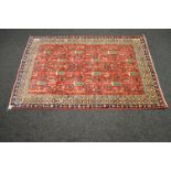 Red ground rug with blue, green and cream pattern and end tassels - 49.