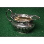 Silver cream jug having gadrooned body and hoop handle,