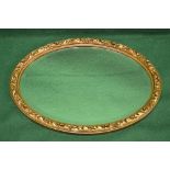 Oval gilt framed wall mirror the frame having raised foliate decoration surmounting an oval