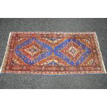Blue ground rug having red and rust pattern - 73" x 36.