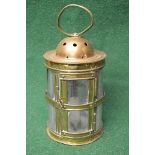 Cylindrical brass lantern having glass shade housing single candle holder and having hoop handle -