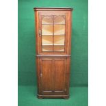 Oak floor standing corner cupboard the upper section having glazed door opening to reveal three