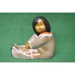 Mid century pottery figure of a young girl with dark hair in a seated position and having an