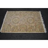 Cream ground rug having pale green, rust and gold pattern with end tassels - 49.