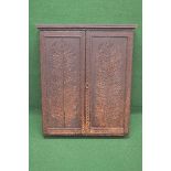 Oak wall hanging cupboard having two carved panelled doors opening to reveal three adjustable