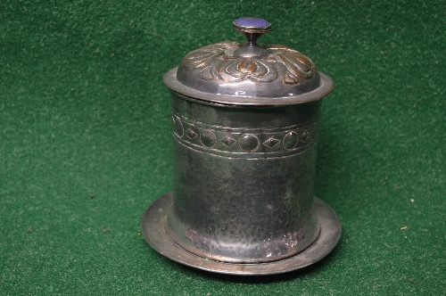 Arts & Crafts silver plated on copper cylindrical tea caddy the lid having embossed decoration of