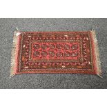 Small red ground rug having brown ground patterned border with end tassels - 22" x 42"