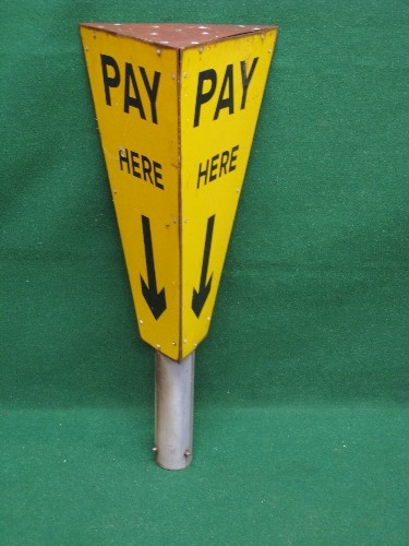 Three sided metal pole mounted Pay Here car park sign, black letters and arrow on a yellow