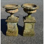 Pair of circular garden urns having gadrooned bodies, standing on square bases and square stepped