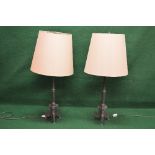 Pair of base metal table lamps the shades being supported by turned column leading to a triform base