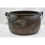 An antique copper cooking pot with iron handle.