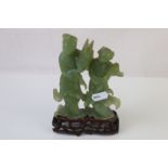 A pair of oriental carved Jadeite figures on a hardwood stand.