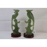A pair of oriental carved Jadeite birds perched on branches on hardwood stands.
