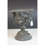 A 19th century bronze two handled cup profusely decorated with grape vines mounted on a stone base