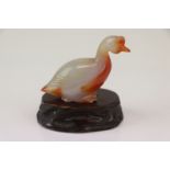 A small carved jade duck on wooden base.
