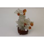 An oriental carved Jadeite cherry blossom ornament on a hardwood stand.