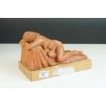 A contemporary sculpture of a recumbent woman raised on a wooden plinth by Ivor Plummer.