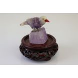 A carved agate bird on wooden base.