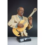 A 20th century resin figure of a blues guitarist on plinth.