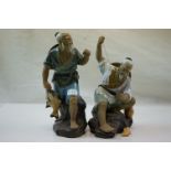 Two ceramic oriental figure of fisherman with catch.
