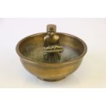 A vintage brass ashtray with central figure.