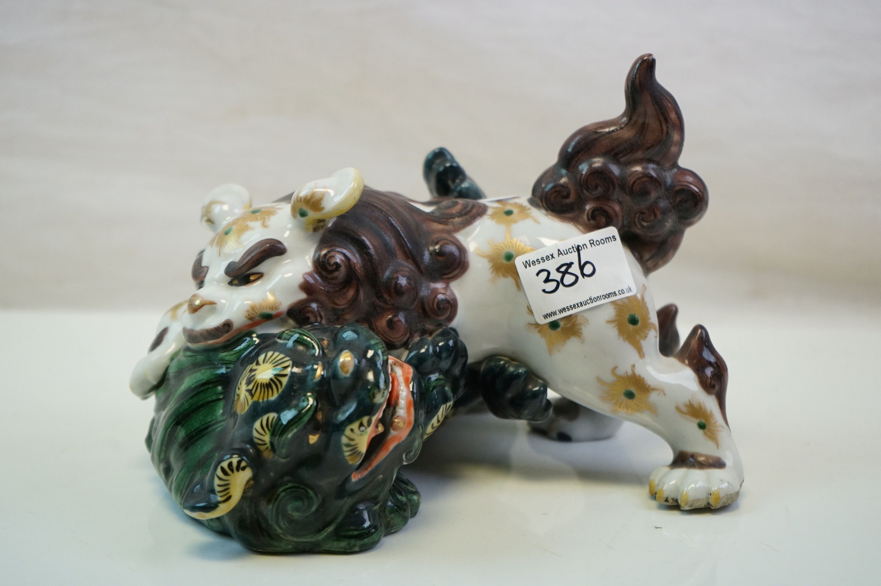 A ceramic Japanese figure of two lions fighting.