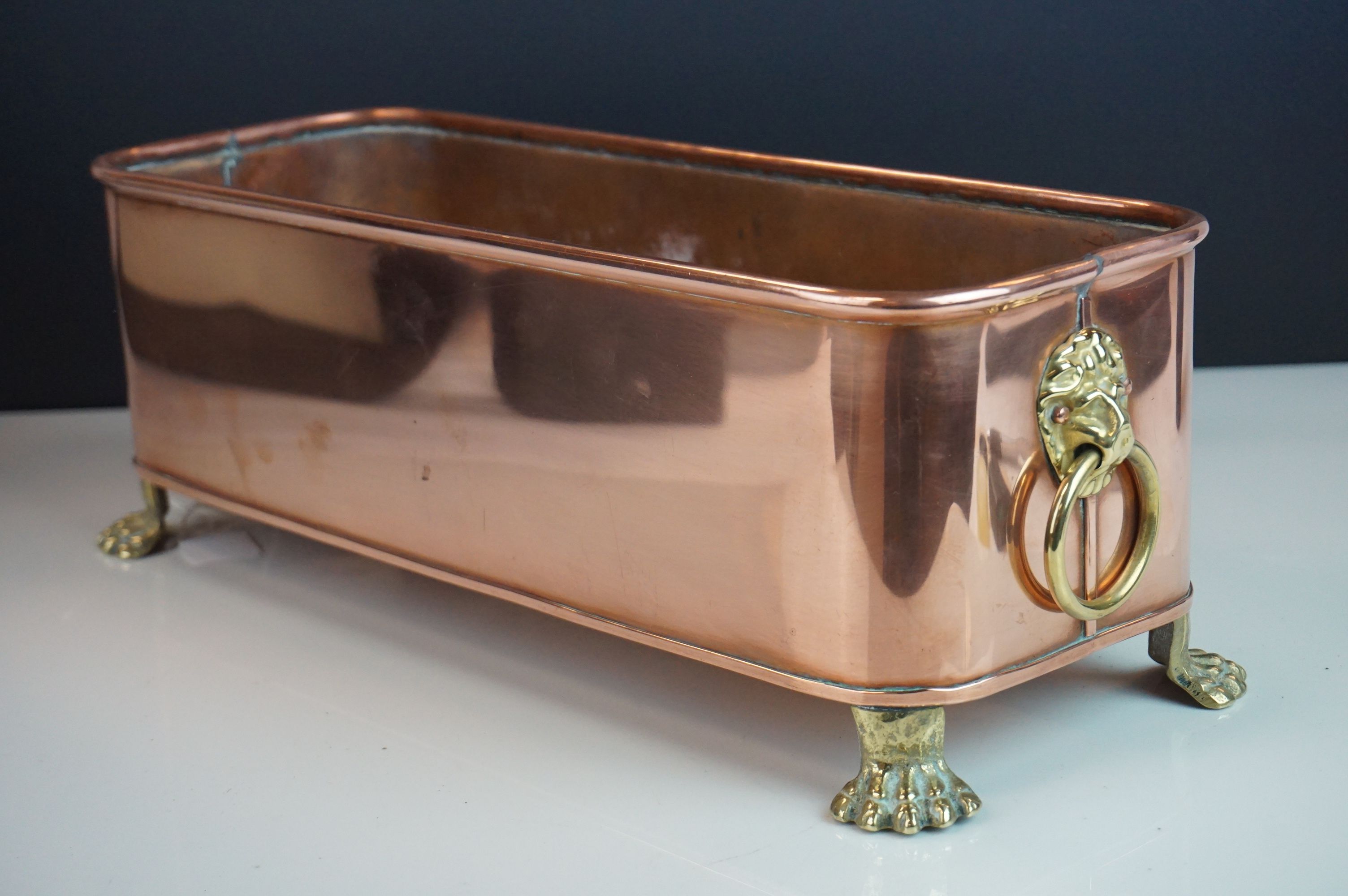 Copper Rectangular Planter with Brass Lion Mask Ring Handles and raised on four brass lion paw feet,