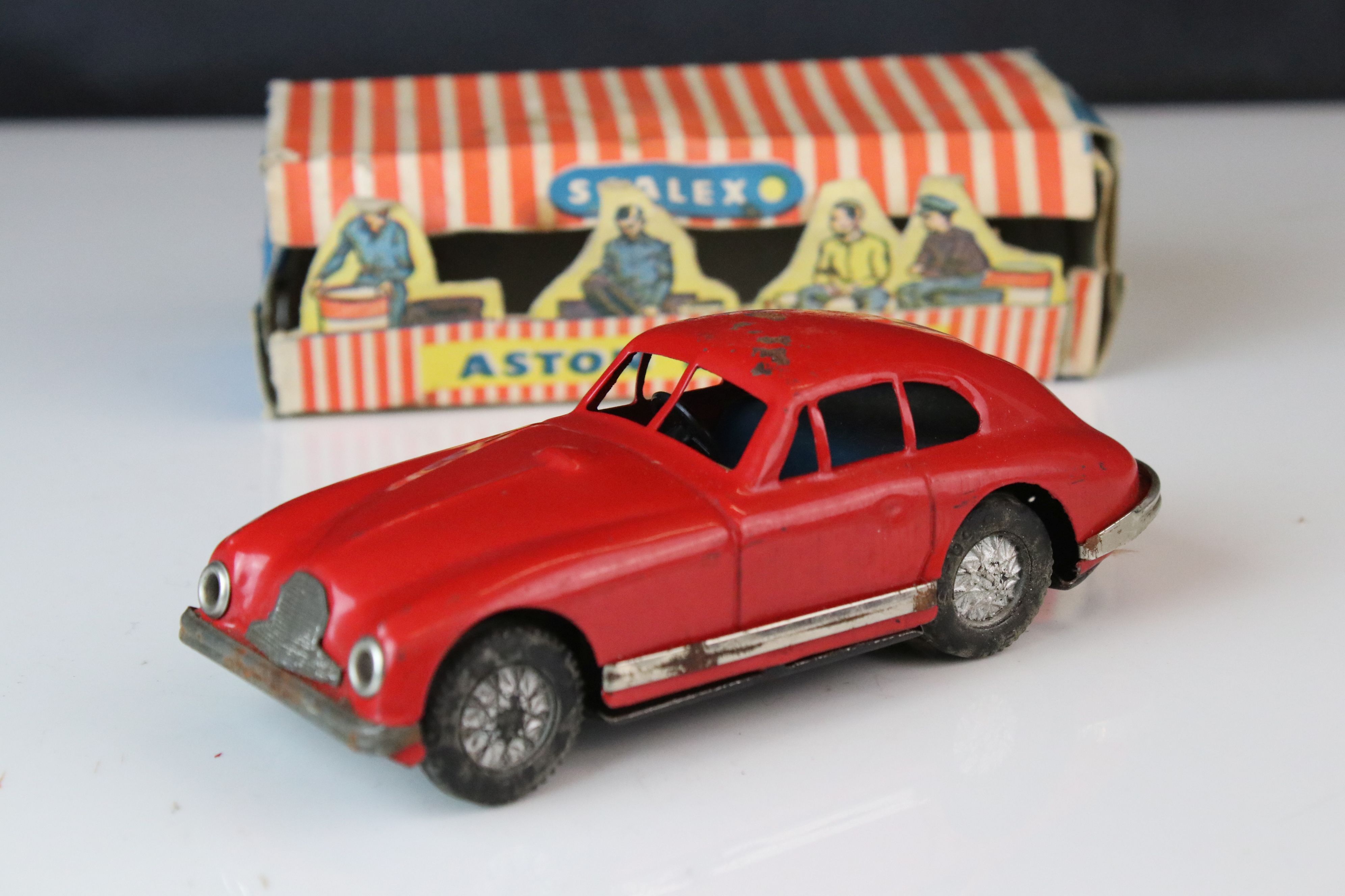 Boxed Scalex tin plate clockwork Aston Martin DB2 model in red, showing play wear with wear to