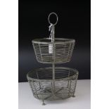 A vintage two tier metal and wire egg stand with ring topped handle.