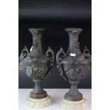 A pair of bronzed spelter two handled urn vases of classical form mounted on marble bases originally