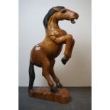A large carved wooden figure of a rearing horse