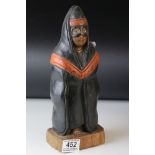 Carved Wooden Figure of a Masked Person wearing a Hooded Cape, possibly South American, 29cms high