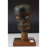 A wooden tribal style head on plinth.