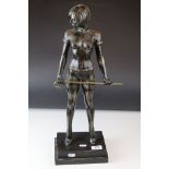 A bronze statue of a female Dominatrix with cane.