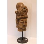 A carved wooden bust of an Asian woman mounted on a metal base.