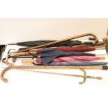 A collection of vintage walking sticks and umbrellas.