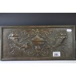 An antique brass wall plaque with classical decoration.