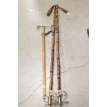 A pair of vintage cane Ski poles together with a wooden handled pick.
