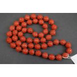 A vintage Chinese Cinnabar beaded necklace with floral decoration.