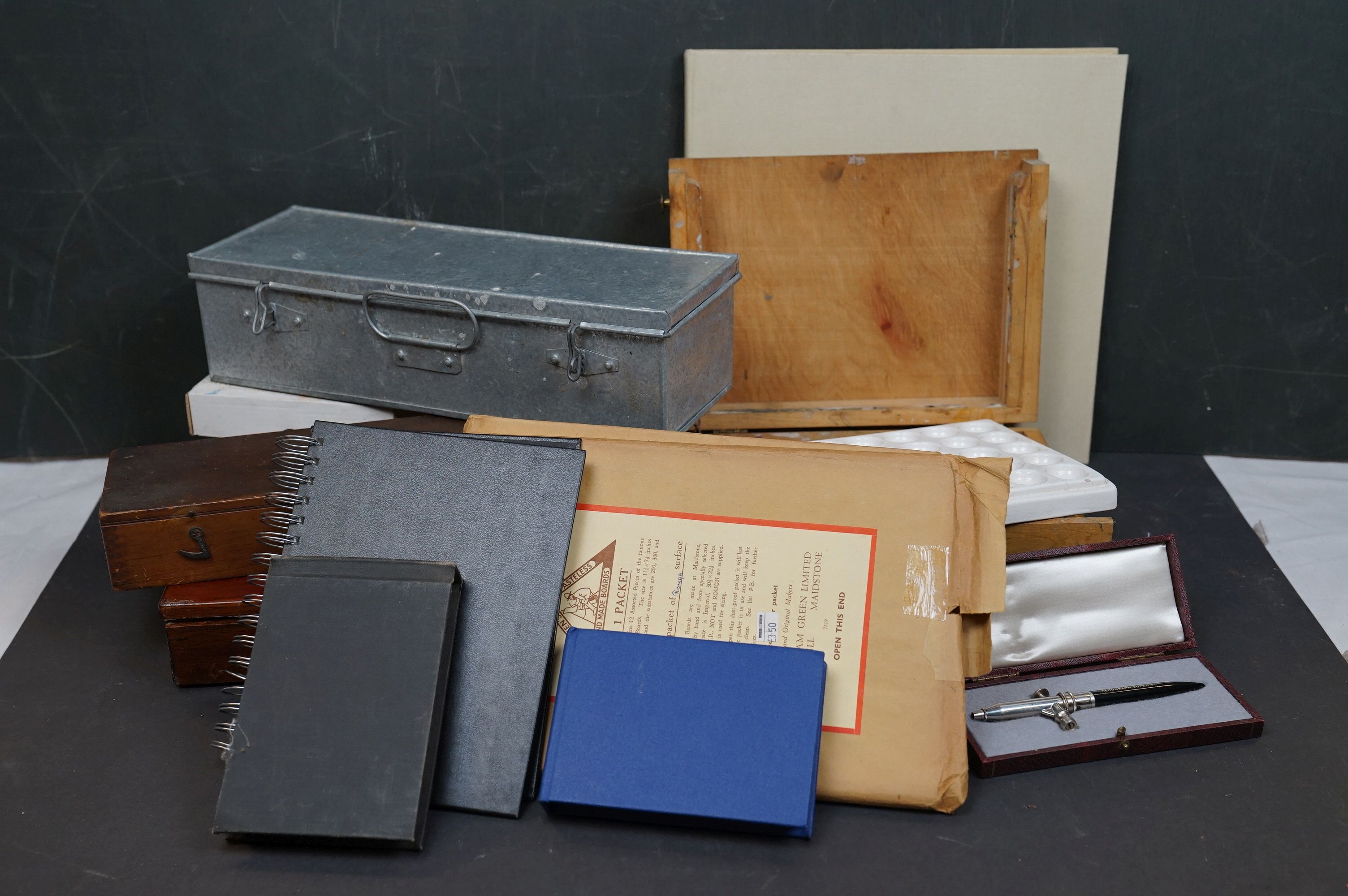 A collection of vintage art supplies and drawing equipment within wooden boxes.