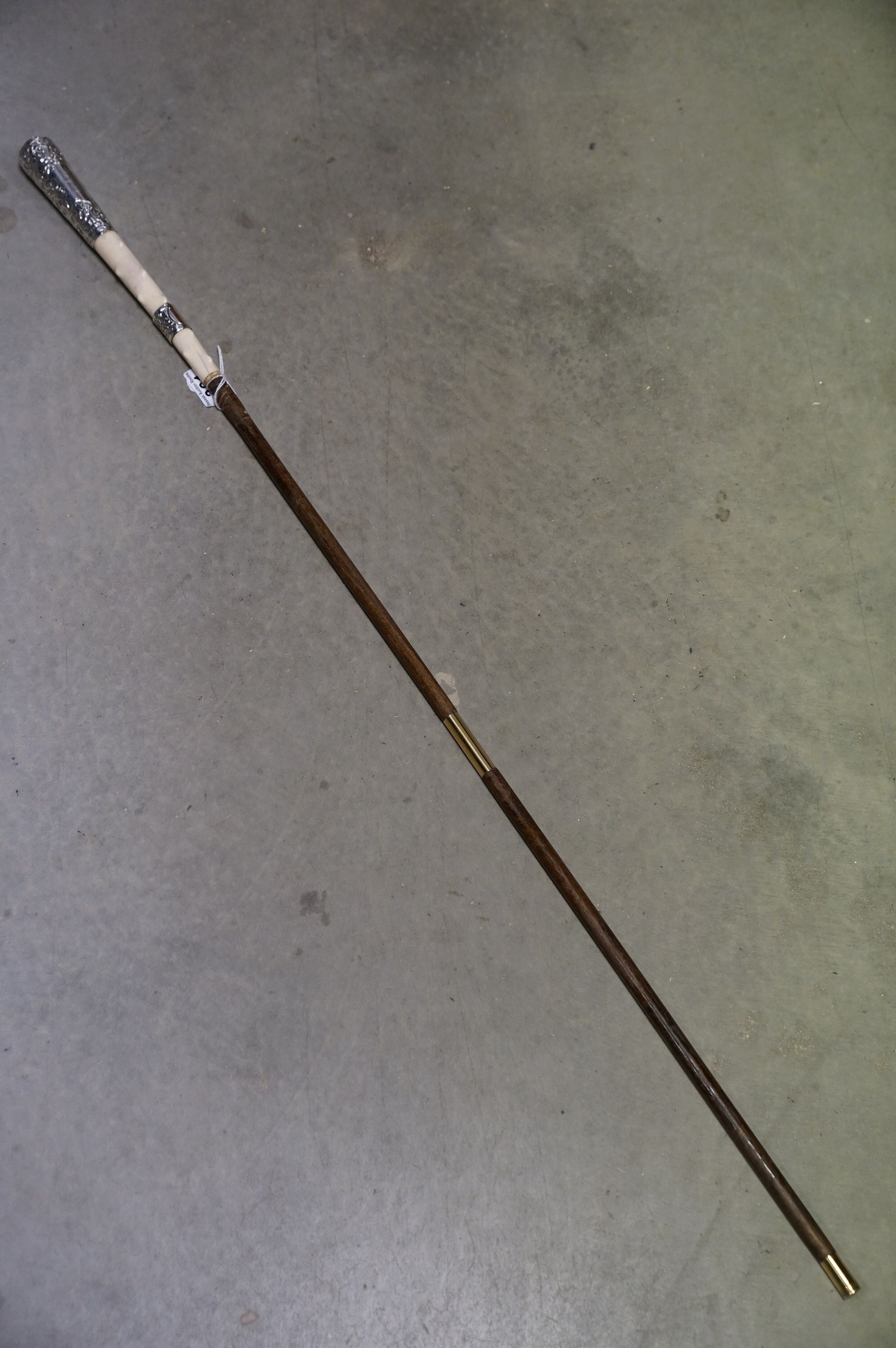 An antique walking cane with silver and ivory knobbled handle and later brass ferrules.