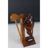 A Taxidermy toad playing harp mounted to wooden stand.