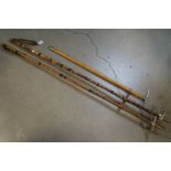 A pair of vintage cane Ski poles together with a wooden handled pick.