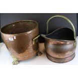 A riveted copper coal bucket with brass lion feet together with another copper coal bucket.