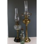 Two vintage brass column oil lamps complete with glass chimneys together with a ship in a bottle.