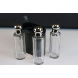 Three glass perfume / cologne bottles with silver plated screw top lids and glass stoppers in a